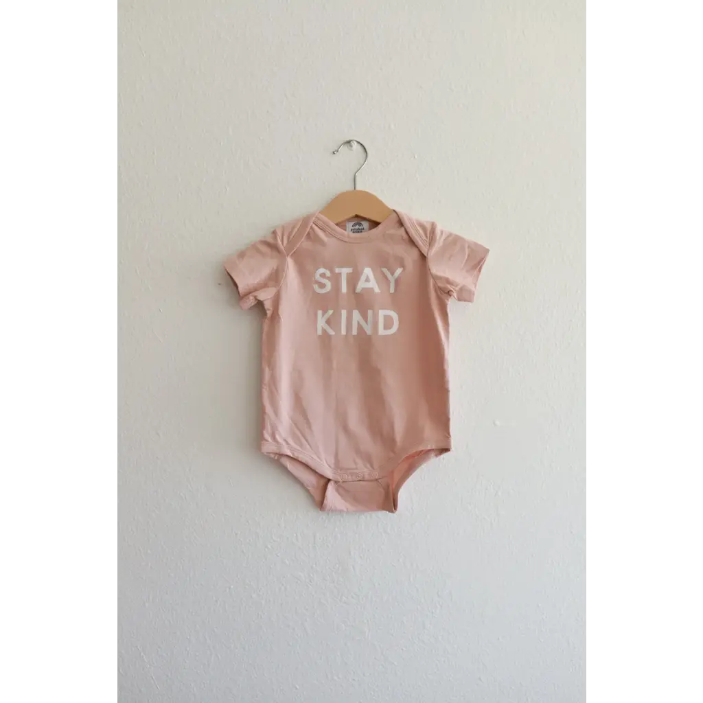 Cute pink baby onesie in organic cotton fabric features Stay Kind slogan for little ones
