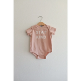 Cute pink baby onesie in organic cotton fabric features Stay Kind slogan for little ones