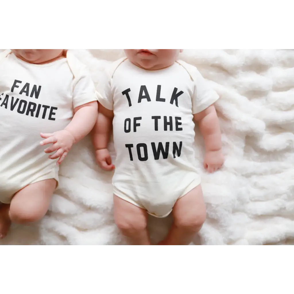 Two cute baby onesies in organic cotton with FAN FAVORITE and TALK OF THE TOWN text