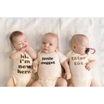 Three babies in cream organic cotton onesies with fun messages, perfect for Tater Tot Organic