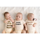 Three babies in cream organic cotton onesies with fun messages, perfect for Tater Tot Organic