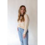 Person in a cream Annie Cardigan Sweater and light blue jeans looking stylish