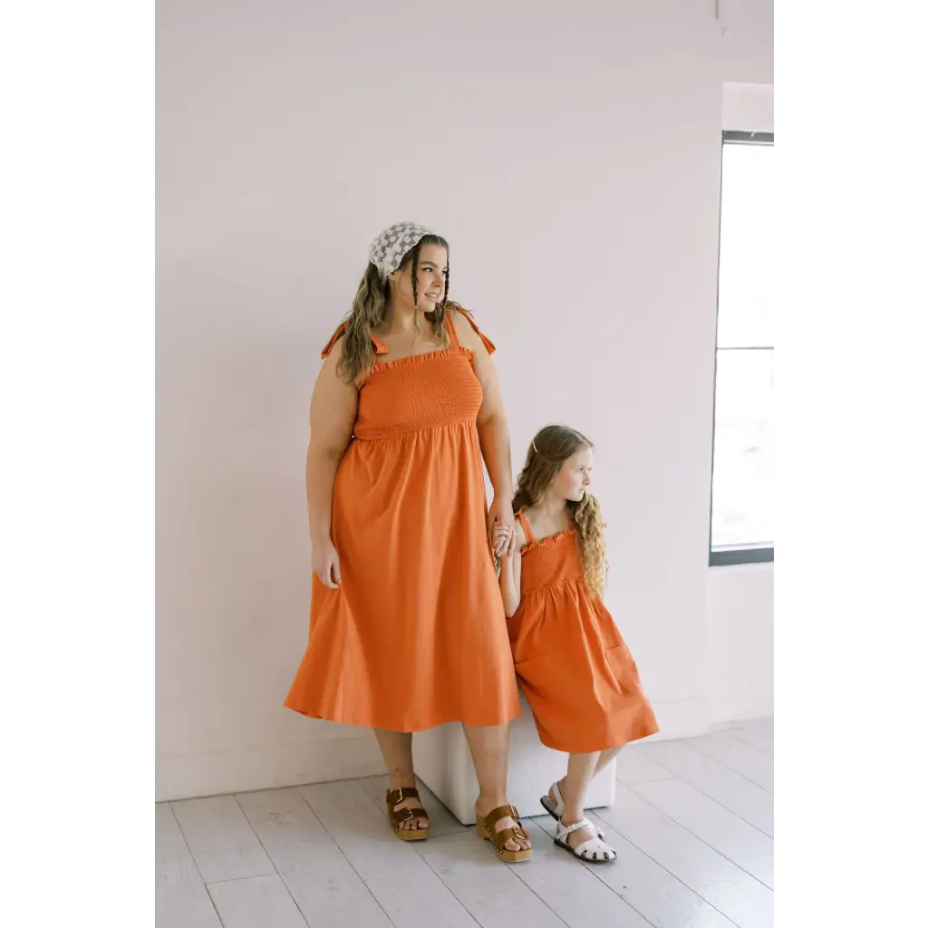 Matching orange day dresses with gathered waists and tied shoulder straps