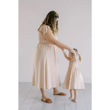 Cream-colored day dress with flutter sleeves and smocked bodice, perfect for sunny days