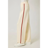 Cream-colored tracksuit pants with red stripes and elastic waistband, perfect for casual style