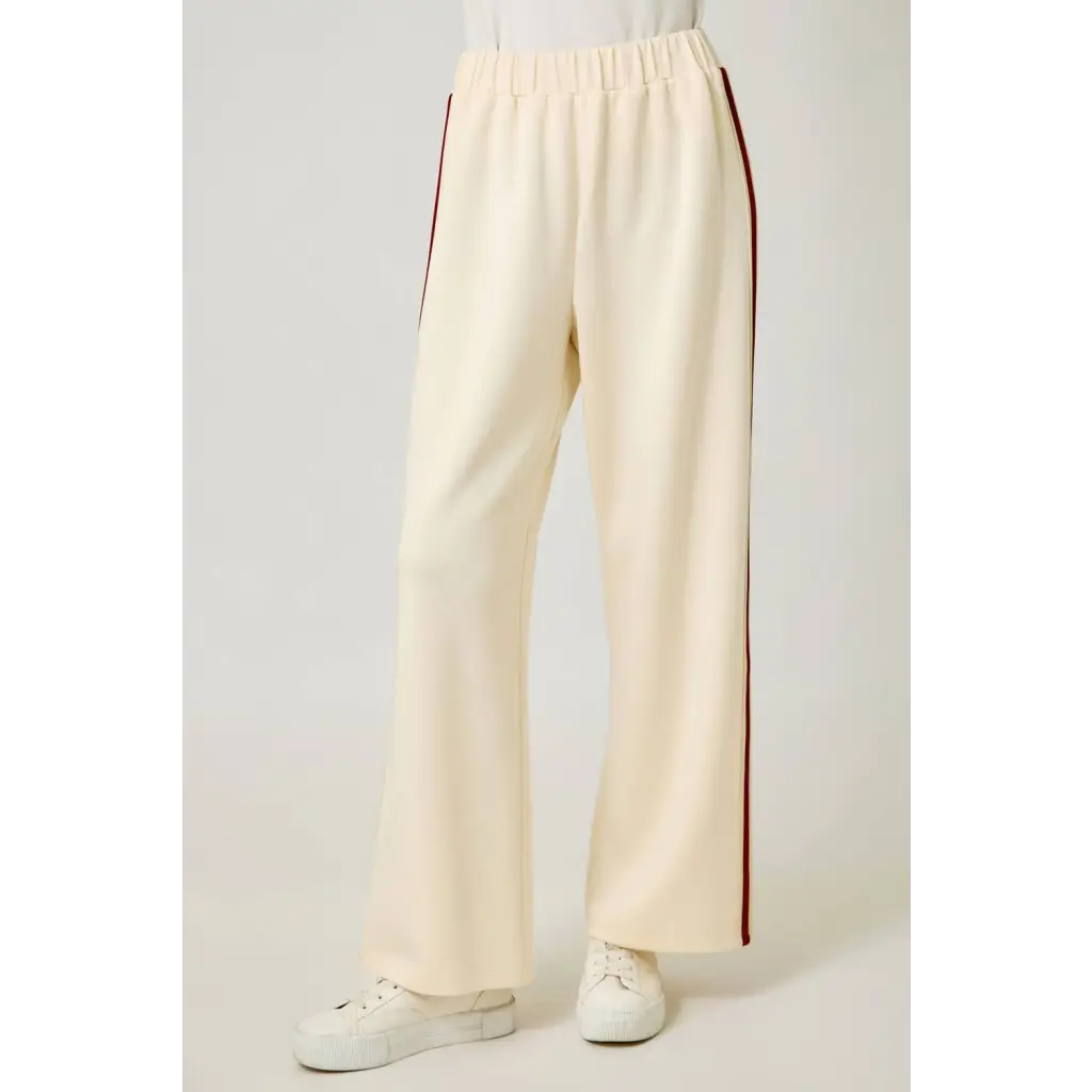 Cream tracksuit pants with red side stripes and elastic waistband for a comfy look