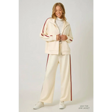 Cream and red tracksuit pants with polished prints, elastic waistband, and white sneakers
