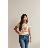 Person rocking a Cream Love Graphic T-shirt with polished prints and blue jeans