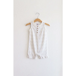 White sleeveless henley romper with polka dots hanging on a wooden hanger. Super soft organic cotton