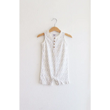 White sleeveless henley romper with polka dots hanging on a wooden hanger. Super soft organic cotton