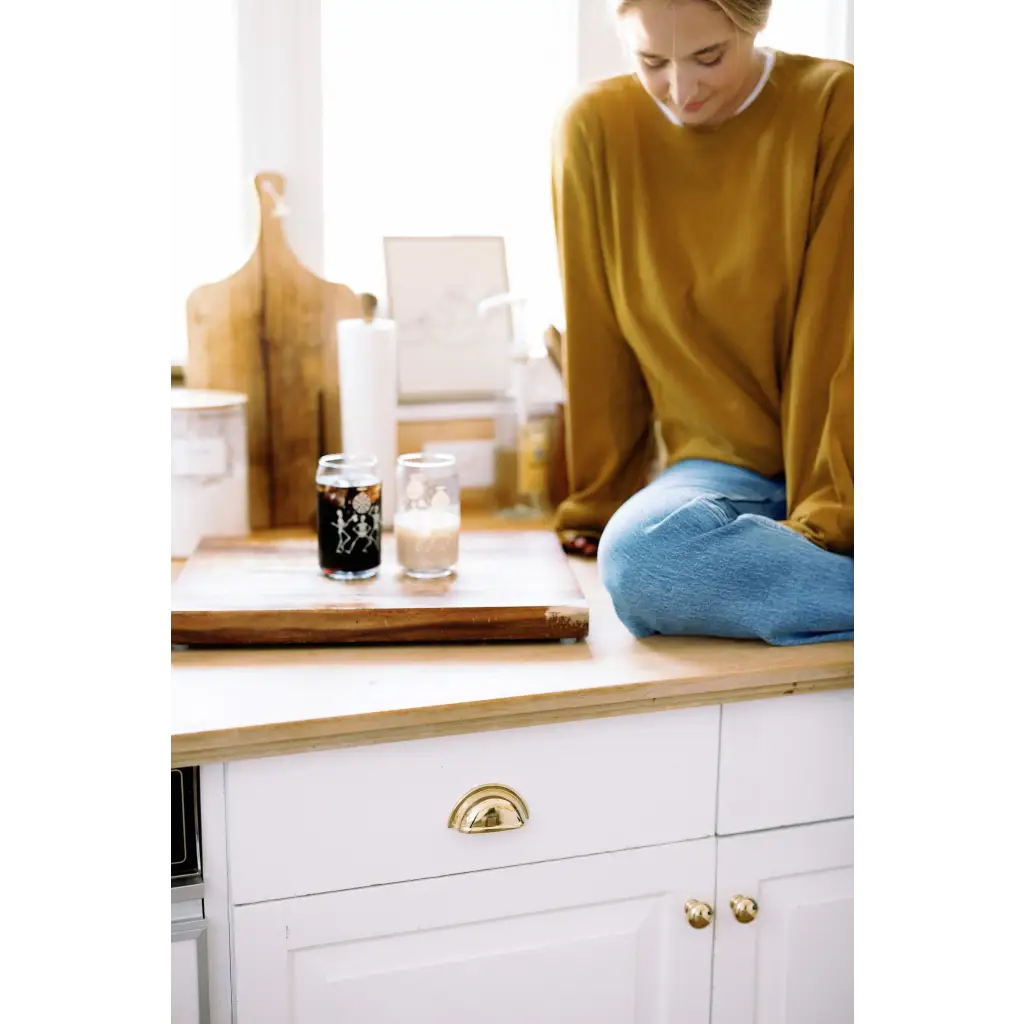 Person in a mustard yellow Jenna Knitted Waffle Longsleeve Pullover on a white cabinet