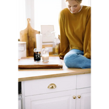 Person in a mustard yellow Jenna Knitted Waffle Longsleeve Pullover on a white cabinet