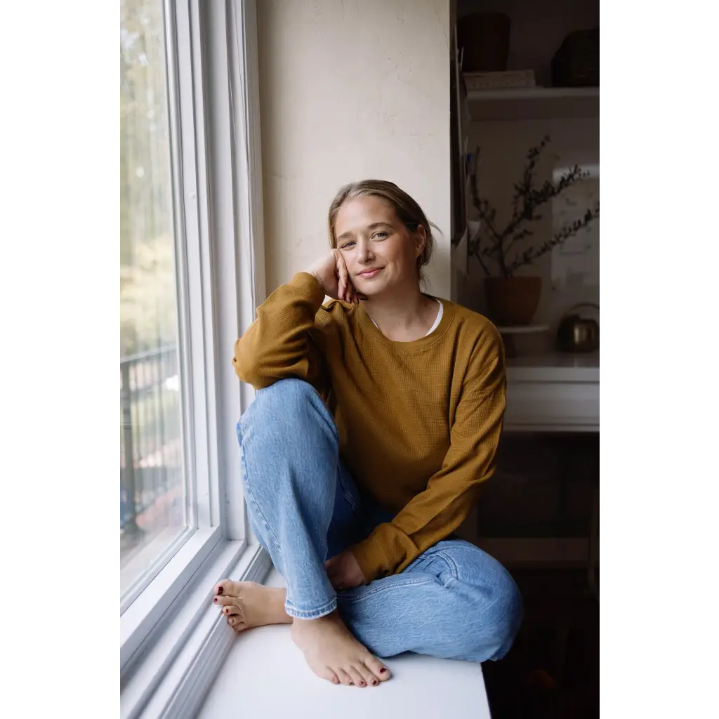 Person in a mustard yellow Jenna Knitted Waffle Longsleeve Pullover by a window
