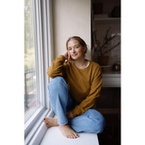 Person in a mustard yellow Jenna Knitted Waffle Longsleeve Pullover by a window