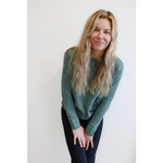 Person in a sage green Margo Crew Neck Sweater and dark pants, showing casual style