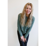 Person in a sage green Margo Crew Neck Sweater and dark pants, showing casual style