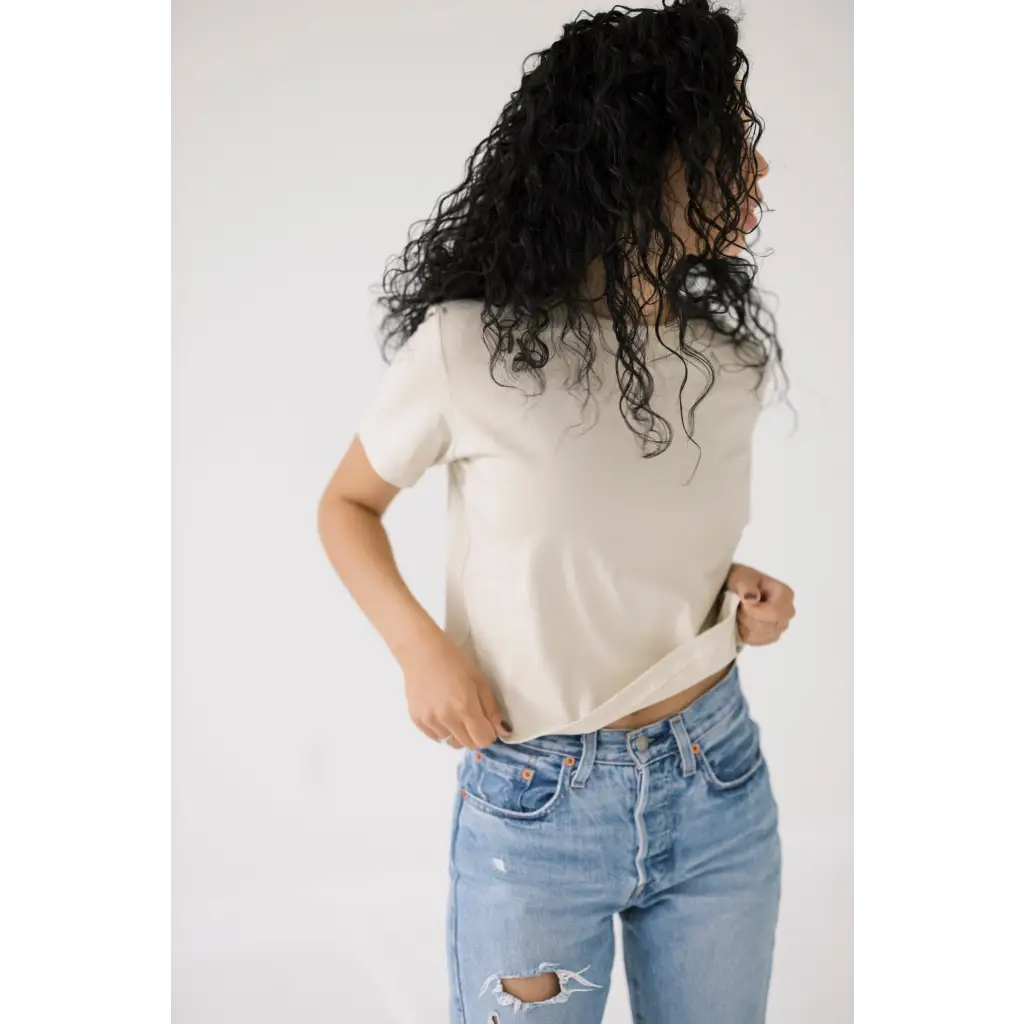 Curly dark hair with a Chill in the Mom Crop Tee in Bone White and distressed jeans