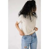 Curly dark hair with a Chill in the Mom Crop Tee in Bone White and distressed jeans