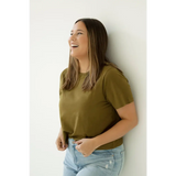 Person in an olive green mom crop boxy tee and light blue jeans laughing joyfully