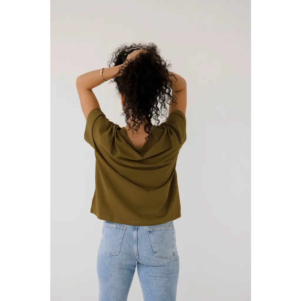 Person in an olive green mom crop boxy tee and light blue jeans, showing off casual style
