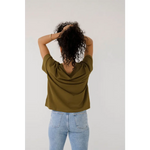 Person in an olive green mom crop boxy tee and light blue jeans, showing off casual style