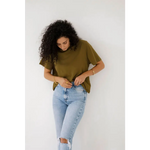 Curly-haired person rocks an olive mom crop boxy tee with ripped light blue jeans