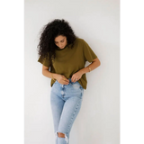 Curly-haired person rocks an olive mom crop boxy tee with ripped light blue jeans