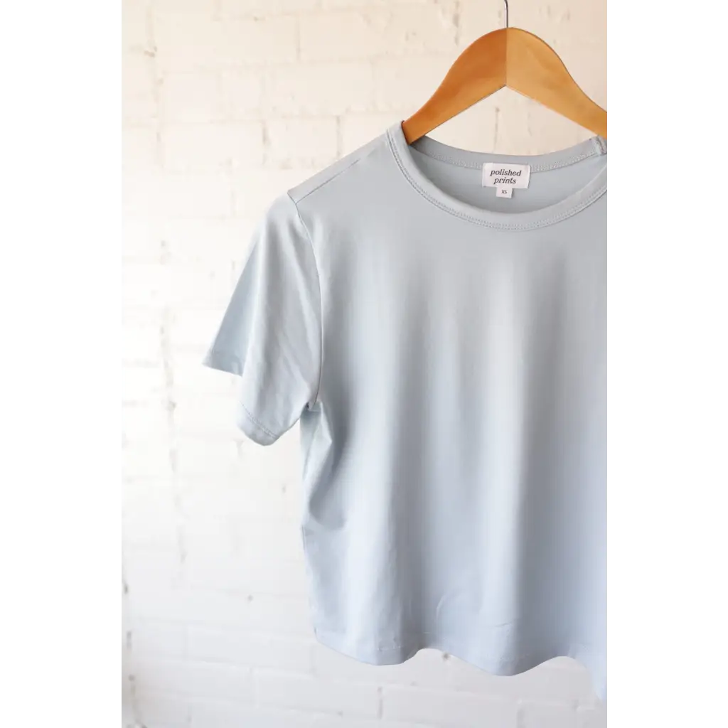 Light blue mom crop T-shirt on wooden hanger from The Mom Crop with polished prints