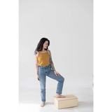 Person in a Mustard Yellow Mom Tank Top and blue jeans, a must-have for stylish womens clothes