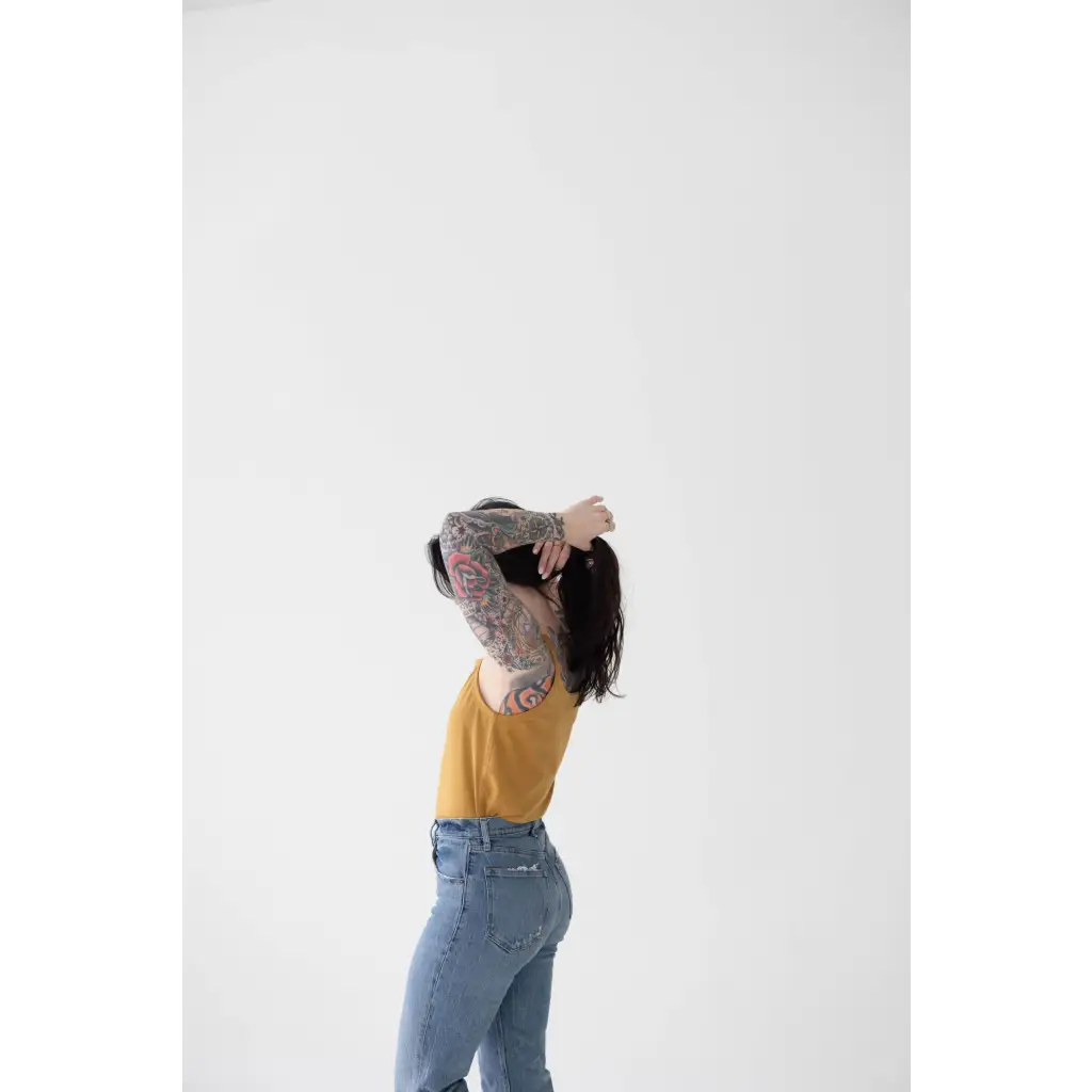 Person in yellow mom tank and blue jeans shows off stylish womens clothes vibe