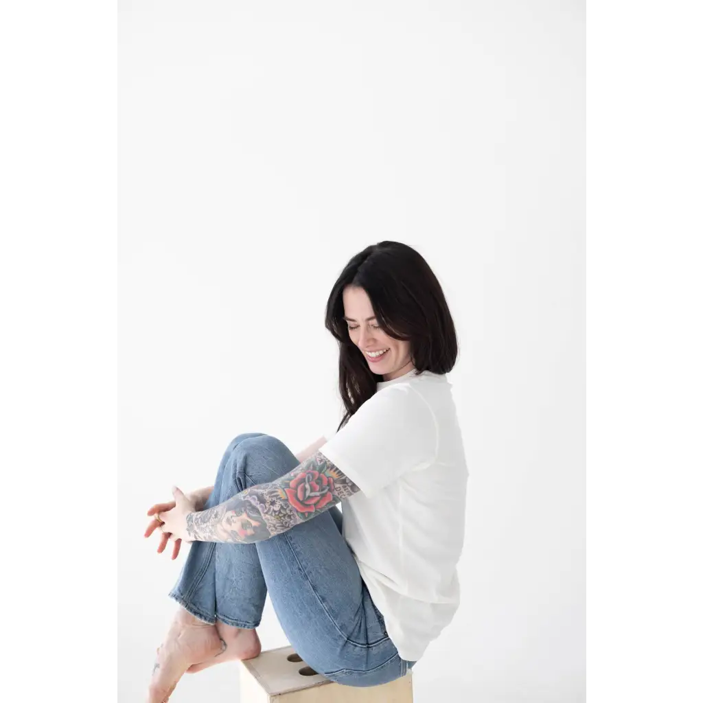 Person in a white sweater and blue jeans enjoying the comfy Mom Tee in Organic Cotton