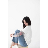 Person in a white sweater and blue jeans enjoying the comfy Mom Tee in Organic Cotton