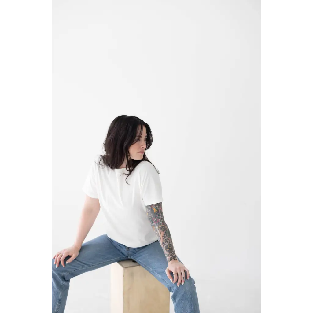 Person in a white mom tee made of organic cotton and spandex blend, sitting stylishly