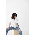 Person in a white mom tee made of organic cotton and spandex blend, sitting stylishly