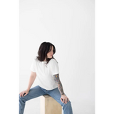 Person in a white mom tee made of organic cotton and spandex blend, sitting stylishly