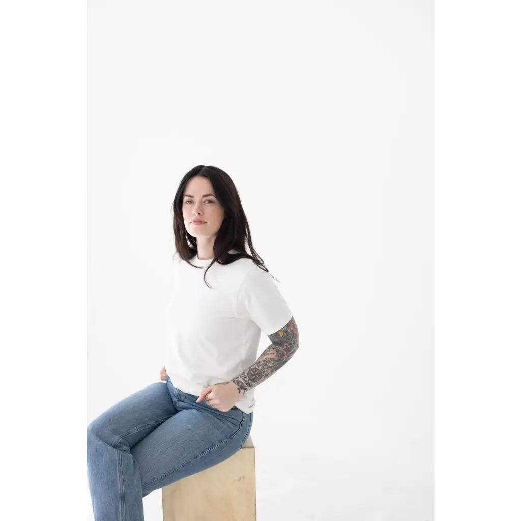 Person in a white mom tee made of organic cotton and spandex blend, sitting stylishly