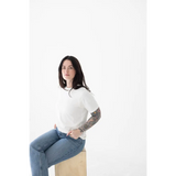 Person in a white mom tee made of organic cotton and spandex blend, sitting stylishly