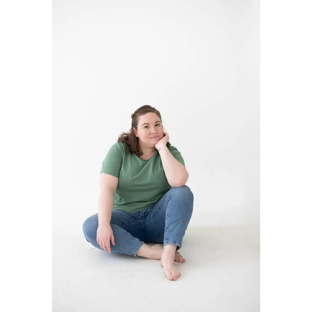 Person in a green Mom Tee made of organic cotton and spandex blend sits cross-legged