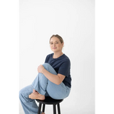 Person sitting on a black wooden stool, styled in a spandex blend mom tee and jeans