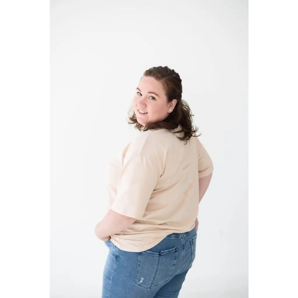 Person in a beige sweater and blue jeans showcasing the Cream Mom Tee in Organic Cotton Spandex Blend