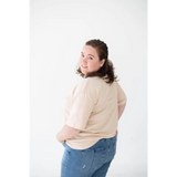 Person in a beige sweater and blue jeans showcasing the Cream Mom Tee in Organic Cotton Spandex Blend