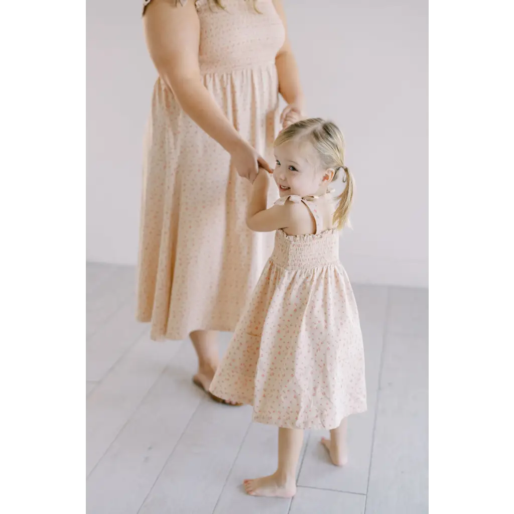 Two kids in matching cream smock dresses, perfect for playtime and mini floral fun