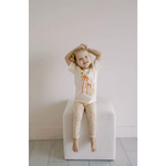 Child in cream pajamas with orange palm trees, perfect for dreams of distant galaxies