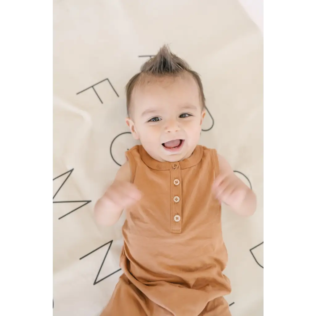 Joyful baby in a caramel Henley Shorty Romper, perfect for little explorers