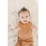 Joyful baby in a caramel Henley Shorty Romper, perfect for little explorers