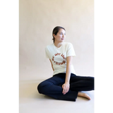White Change Graphic T-shirt with circular design, styled with dark jeans in a relaxed pose
