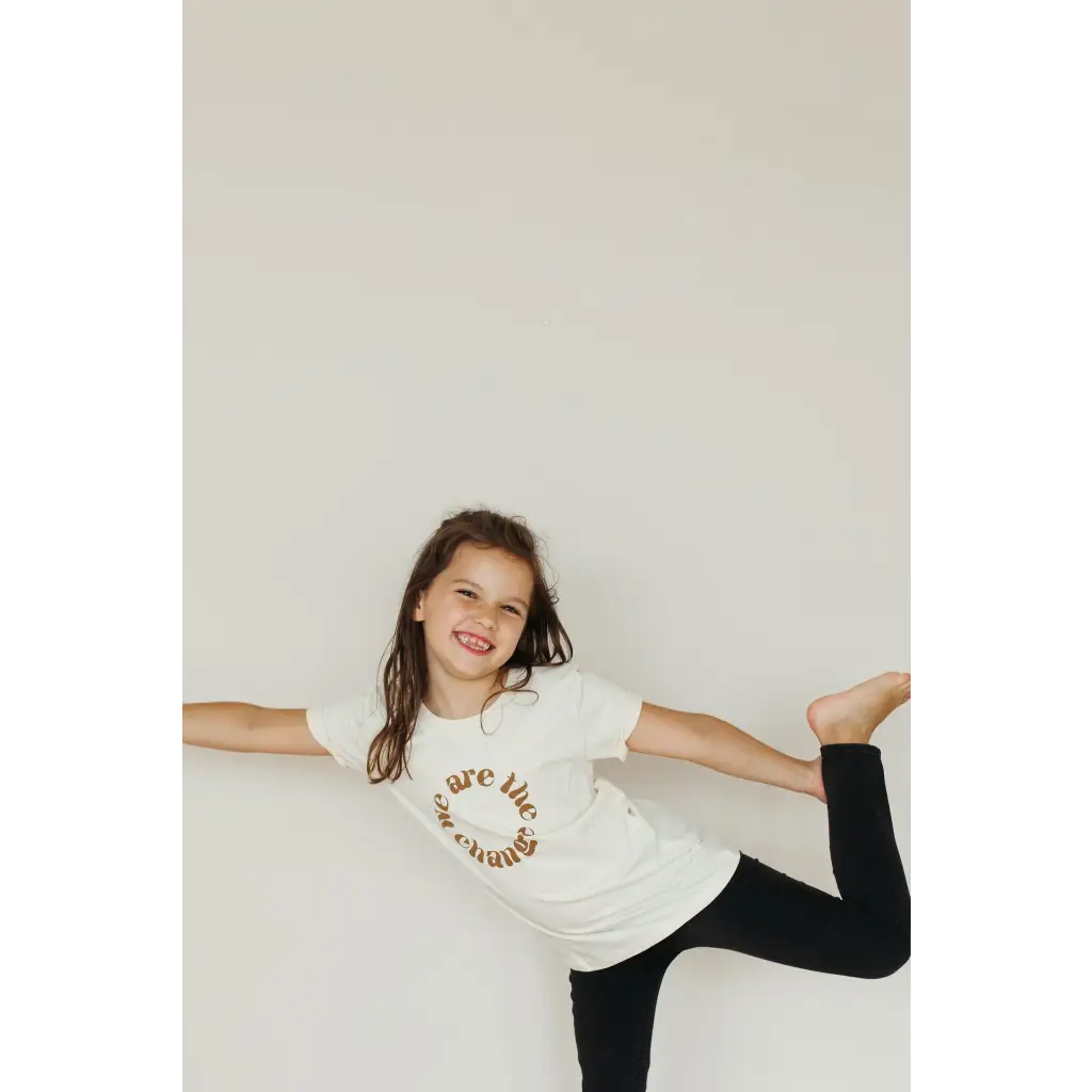 Playful kid in a white organic cotton tee and black leggings rocking polished prints