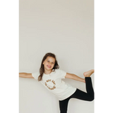 Playful kid in a white organic cotton tee and black leggings rocking polished prints