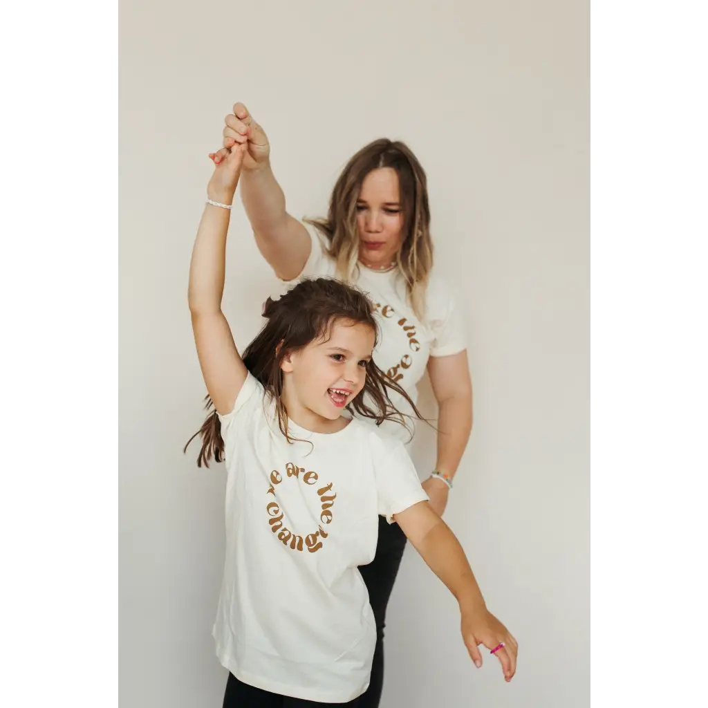 Two kids in matching organic cotton tees dancing joyfully in fun polished prints