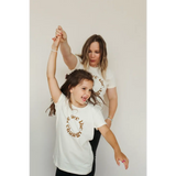 Two kids in matching organic cotton tees dancing joyfully in fun polished prints